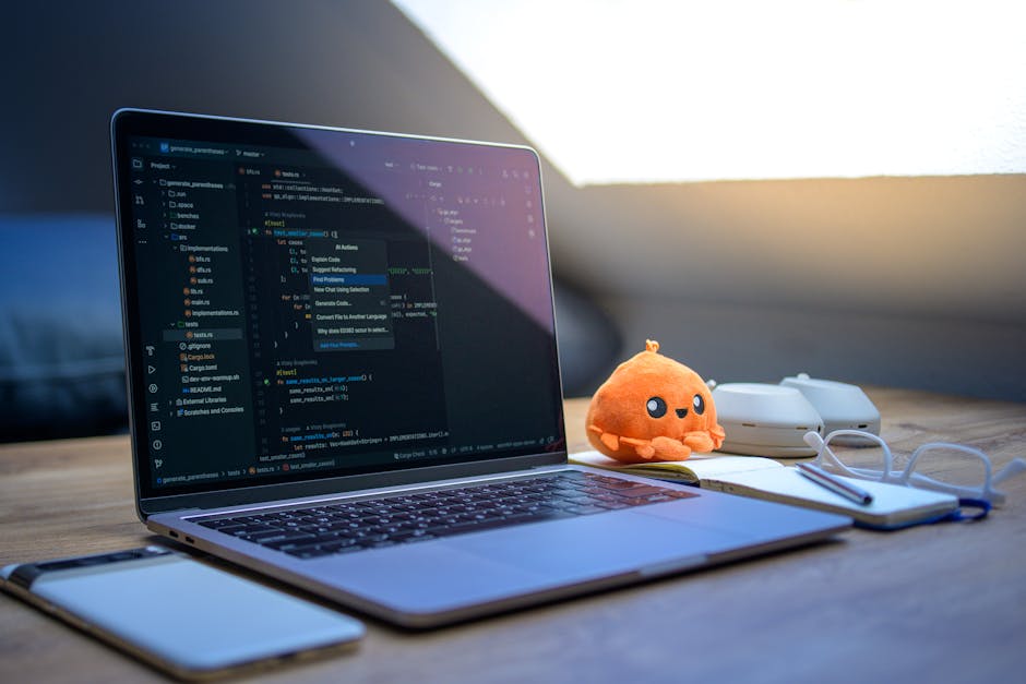 A cozy workspace featuring a laptop displaying code, a smartphone, and a cute orange plush toy.